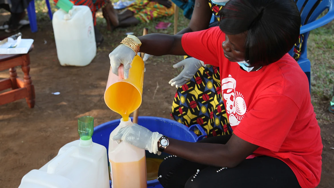 A woman pouring a liquid from a jug to a bottle